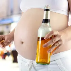 Ciężarna kobieta trzyma papierosa i piwo. To obraz dorosłego dziecka alkoholika w związku, które powiela schematy.