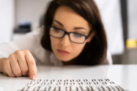 Kobieta w okularach z uwagą układa spinacze, co może sugerować kompulsywne zachowania.