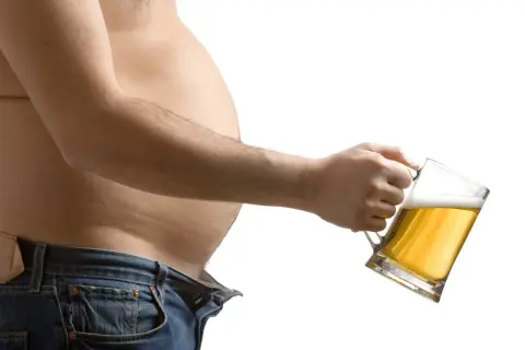 Brzuch i kufel piwa. Czy od alkoholu się tyje? To pytanie nurtuje wielu, gdy widzą takie obrazy.