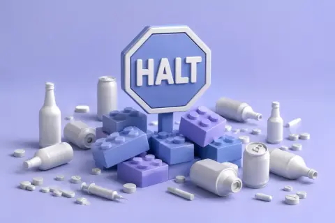 Znak "HALT" otoczony klockami, butelkami, puszkami i pigułkami. To symboliczny program halt, który wzywa do zatrzymania.
