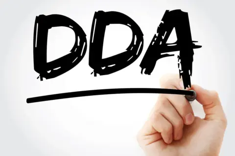 Ręka pisze markerem czarne litery DDA pod linią.