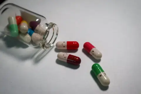Kolorowe kapsułki z uśmiechniętymi buźkami, niektóre wypadły z buteleczki. Czy psychotropy to narkotyki?