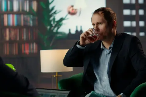 Mężczyzna w garniturze pije whisky, wyglądając na zmęczonego. Czy to obraz wysokofunkcjonującego alkoholika?