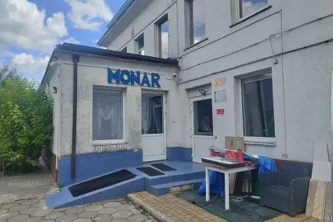 Budynek Monaru z niebieskim napisem, wejściem i otoczeniem.