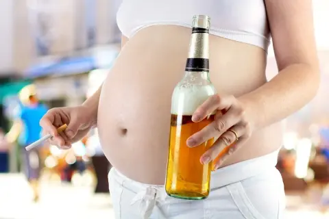 Ciężarna kobieta trzyma papierosa i piwo. To obraz dorosłego dziecka alkoholika w związku, które powiela schematy.