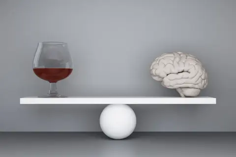Szalka wagi z mózgiem przechyla się, gdy obok pojawia się kieliszek z alkoholem, symbolizując zmianę zachowania po alkoholu.
