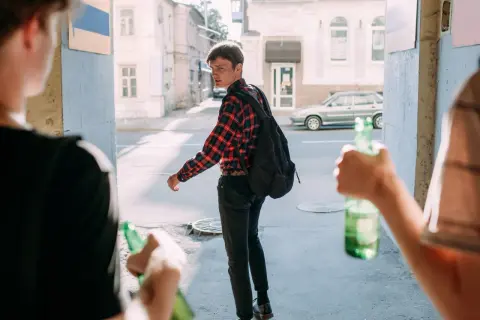 Młodzi ludzie z butelkami piwa. Pamiętaj, co grozi za picie alkoholu w wieku 17 lat.