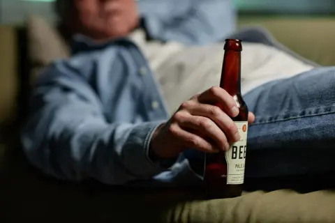 Mężczyzna odpoczywa z butelką piwa, zastanawiając się nad metabolizmem alkoholu.