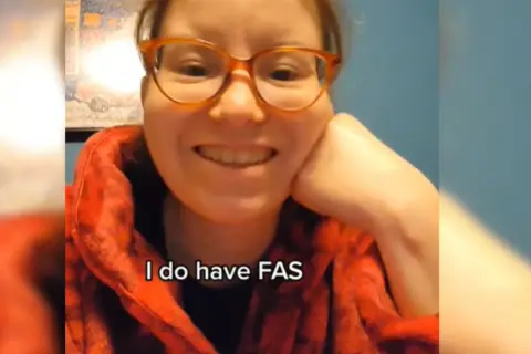 Uśmiechnięta kobieta w okularach mówi: "I do have FAS". Opowiada o FAS u dorosłych.