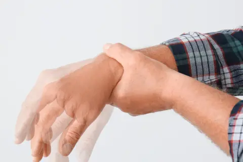 Drżąca ręka mężczyzny w kratę, symbolizująca zespół abstynencyjny. Leki mogą pomóc złagodzić objawy.