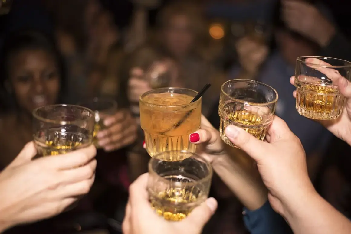Grupa ludzi wznosi toasty. Trudno ocenić ile alkoholu we krwi, ale zabawa trwa.