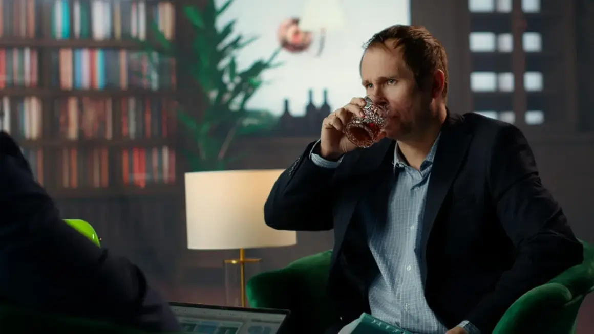 Mężczyzna w garniturze pije whisky, wyglądając na zmęczonego. Czy to obraz wysokofunkcjonującego alkoholika?