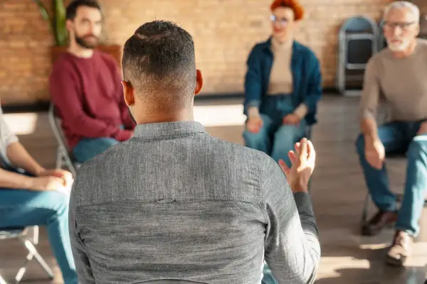 Grupa ludzi na sesji terapeutycznej, dyskutująca o tym, jak wyjść z nałogu.