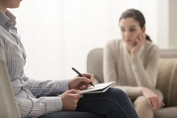 Terapia uzależnień: terapeuta notuje, pacjentka słucha. Zastanawiasz się, ile zarabia terapeuta uzależnień?