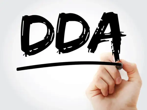 Ręka pisze markerem czarne litery DDA pod linią.