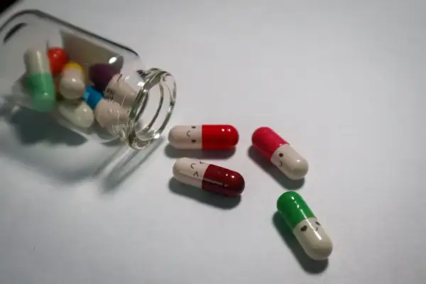 Kolorowe kapsułki z uśmiechniętymi buźkami, niektóre wypadły z buteleczki. Czy psychotropy to narkotyki?