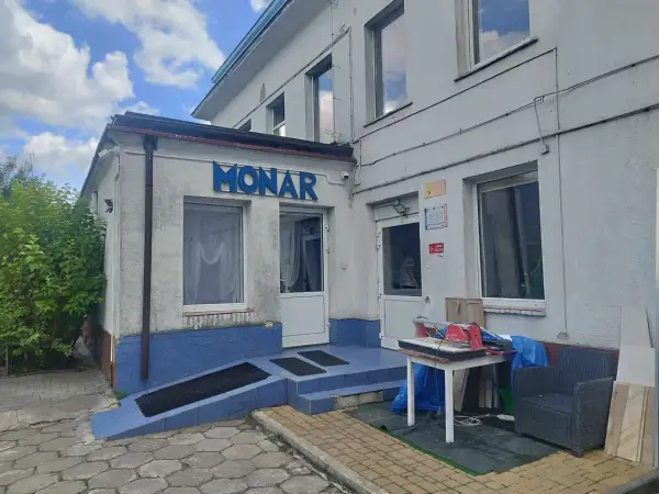 Budynek Monaru z niebieskim napisem, wejściem i otoczeniem.
